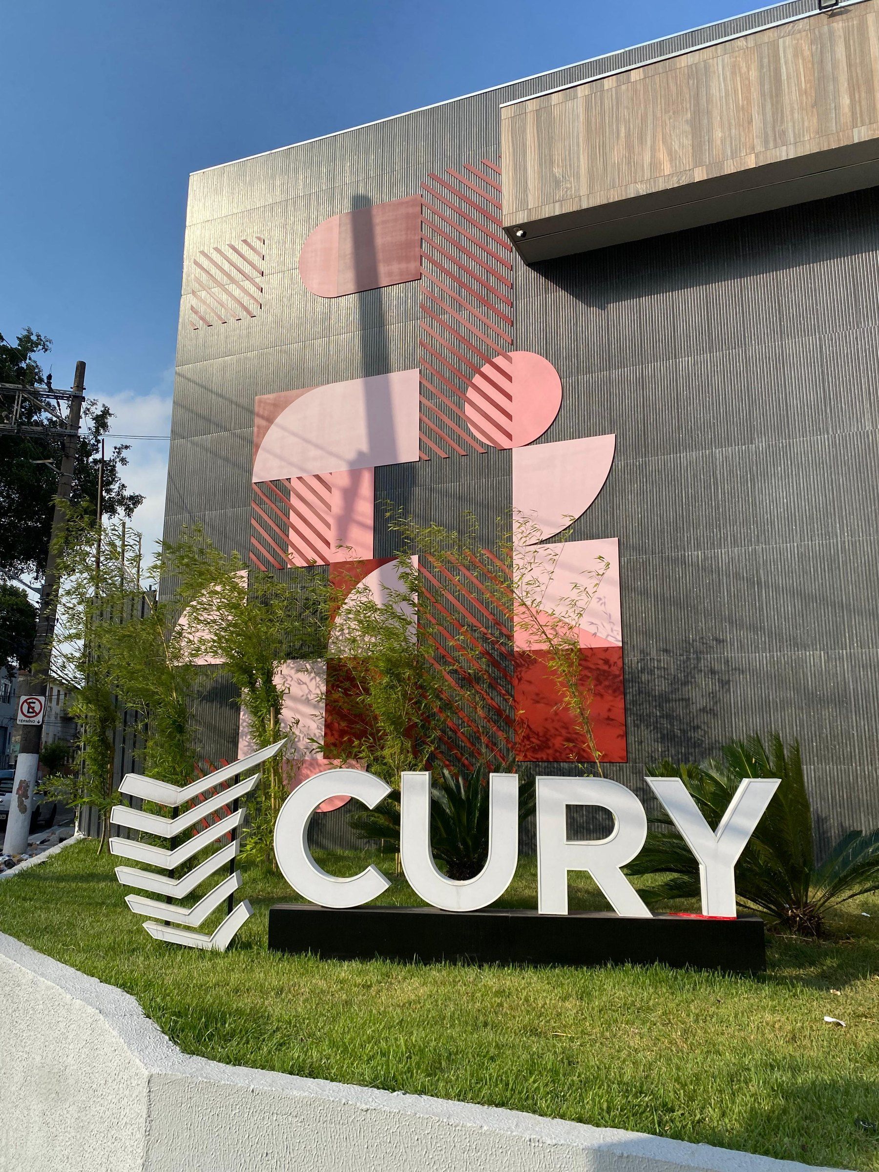 Monumento com o logotipo Cury em letras caixa e escultura colorida no jardim do empreendimento