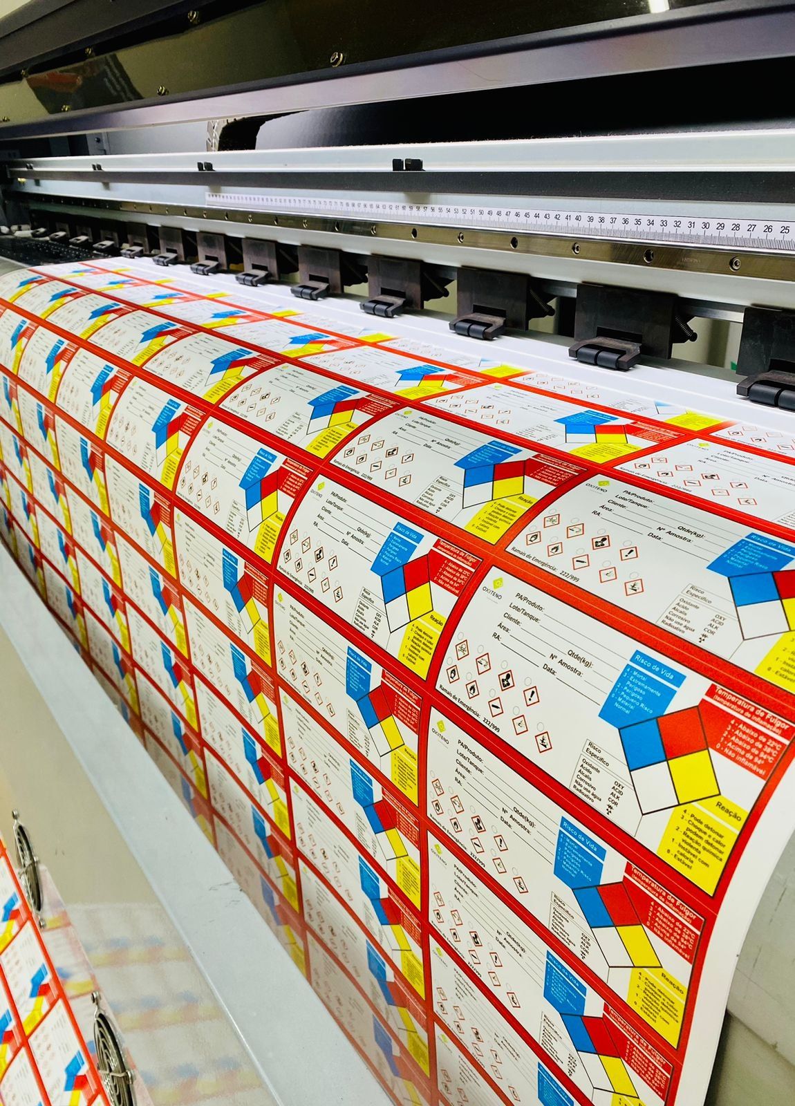Impressora de grande formato imprimindo adesivos de sinalização na produção da Imprimak