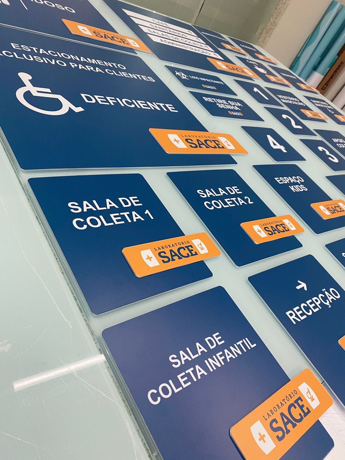 Placas azuis e laranja de identificação de salas do Laboratório Sace